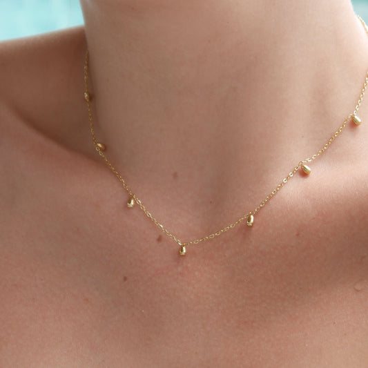 Close-up of a delicate gold necklace on a person's neck with a blurred background